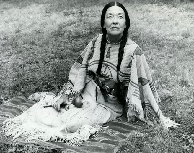 Te Ata in Native American dress, sitting on a blanket